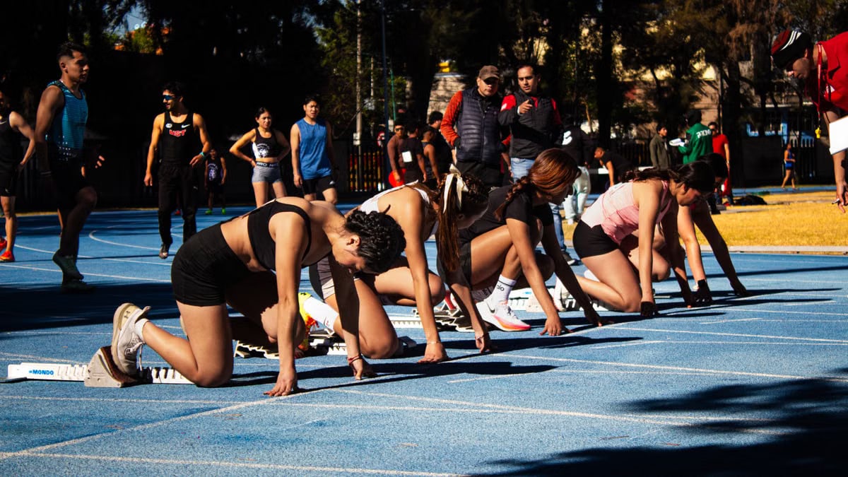 Athletes at starting line on outdoor track, focusing and ready to sprint. Exciting scene at the start of a race.